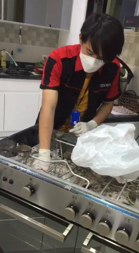 Teknisi memperbaiki kompor standing dan oven di dapur pelanggan